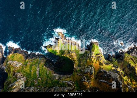 Vue de haut en bas des falaises de Horn Head avec des oiseaux de mer et des vagues de l'Atlantique mousseuses pendant une journée ensoleillée Banque D'Images