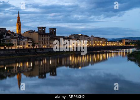 Bâtiments illuminés le long de la rivière Arno se reflétant sur l'eau pendant l'heure bleue dans le centre-ville de Florence, en Italie Banque D'Images