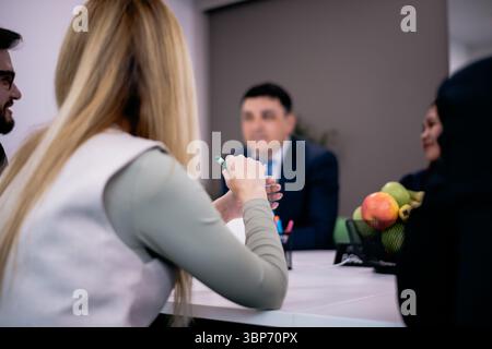 Groupe de professionnels en réunion, discutant des idées et collaborant sur des projets autour d'une table, avec un bol de fruits en arrière-plan ajoutant vibranc Banque D'Images