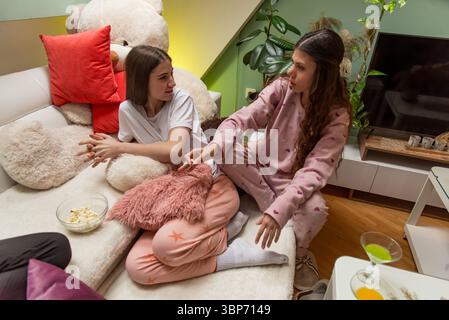 Deux amis passent leur temps à se détendre sur un canapé, à engager une conversation et à profiter de la compagnie de l'autre dans un environnement intérieur confortable. Banque D'Images