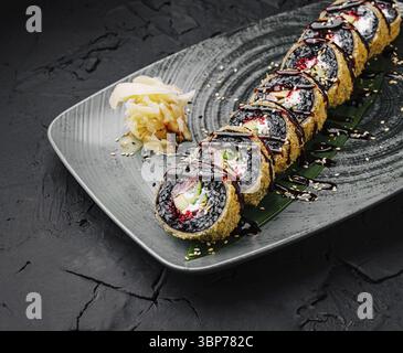 Nourriture, Un plateau vibrant présente des rouleaux de sushi magnifiquement arrangés avec du riz noir et des garnitures colorées, complétés par du gingembre mariné et un dri Banque D'Images