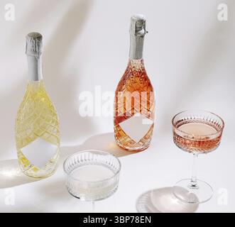 Nourriture, deux élégantes bouteilles de boissons pétillantes reposent sur un fond clair, accompagnées de deux délicats verres à champagne. Parfait pour un gath festif Banque D'Images