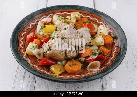 Nourriture, ragoût de poulet avec pommes de terre, oignons, carottes, poivrons et garniture d'aneth servis sur une assiette Banque D'Images