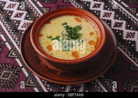 Nourriture, vue de dessus d'une soupe crémeuse vibrante garnie d'herbes, servie dans un bol en terre cuite Banque D'Images