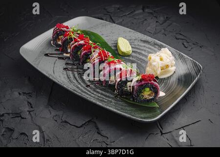 Nourriture, Une variété de rouleaux de sushi colorés sont agencés avec art sur une assiette décorative élégante. Les garnitures adjacentes comprennent du wasabi et du gingembre mariné, spectacle Banque D'Images