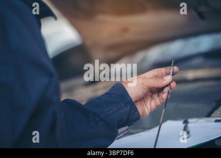 Mécanicien automobile main vérifiant la jauge d'huile moteur mécanique de voiture service sur site. Gros plan main man vérifier le niveau d'huile moteur localiser la jauge, essuyer le chiffon Banque D'Images