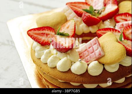 Génoise aux fraises, barres de chocolat au lait rose, asperges argentées, crème à la vanille et petits gâteaux à la cape en forme de coeur. Dessert sucré d'été pour bi Banque D'Images