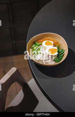 Nourriture, soupe salée de nouilles au poulet avec légumes et œufs servis dans un cadre moderne de restaurant Banque D'Images