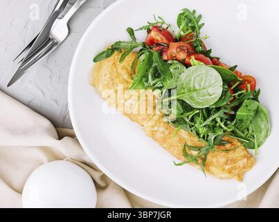 Nourriture, omelette à la roquette, tomates et basilic dans une assiette Banque D'Images