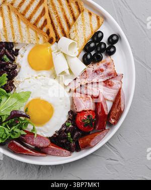 Nourriture, vue aérienne d'une assiette copieux avec œufs, bacon, pain grillé et légumes frais Banque D'Images