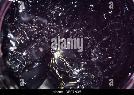 Gel cosmétique dans un pot noir gros plan. gel transparent avec texture et bulles Banque D'Images