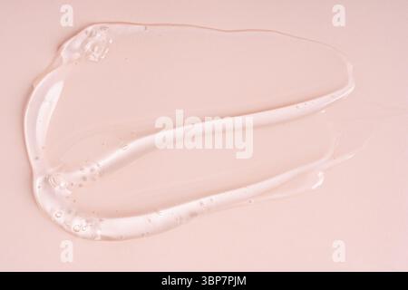 Gros plan de gel cosmétique liquide rose ou de tampons de maquillage sérum avec une texture brillante et brillante sur un fond rose lisse Banque D'Images