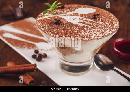 Nourriture, délicieux dessert tiramisu est servi sur une assiette blanche avec des grains de café et des bâtonnets de cannelle Banque D'Images