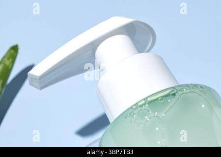 Gros plan de la bouteille de pompe avec nettoyant visage aloe vera sur fond bleu. Emballage cosmétique pour savon, shampooing ou après-shampooing. Vitrine Banque D'Images