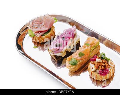 Nourriture, canapés délicats disposés sur un plateau d'argent comportent diverses garnitures. Chaque friandise en bouchée met en valeur des saveurs uniques, parfaites pour un style élégant Banque D'Images