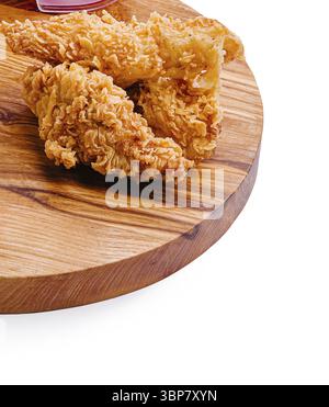 Nourriture, juteux, morceaux de poulet frit brun doré sont élégamment disposés sur un plateau rond en bois. Des tranches de tomates fraîches accompagnent le plat, en fournissant un c Banque D'Images