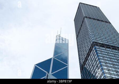 Hong Kong - 15 juillet 2017 : deux gratte-ciels modernes s'élèvent contre le ciel bleu clair, mettant en valeur des conceptions architecturales complexes et un sentiment de pro urbain Banque D'Images