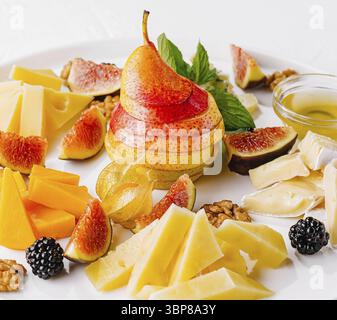 Nourriture, arrangement élégant de divers fromages, figues fraîches, poire et noix sur une plaque en céramique Banque D'Images