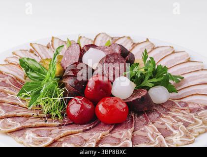 Nourriture, variété de charcuteries tranchées servies sur une assiette avec garniture, isolé sur fond blanc Banque D'Images