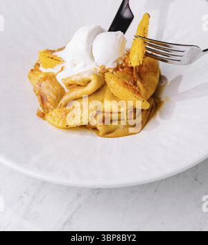 Nourriture, délicieuses crêpes dessert boule de crème glacée avec garniture de zeste d'orange, fourchette en action Banque D'Images