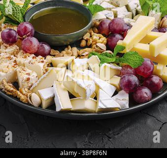 Nourriture, Un plat magnifiquement arrangé avec une variété de fromages, raisins, noix, et un plat de miel. Cette configuration est parfaite pour un rassemblement ou une célébrité Banque D'Images