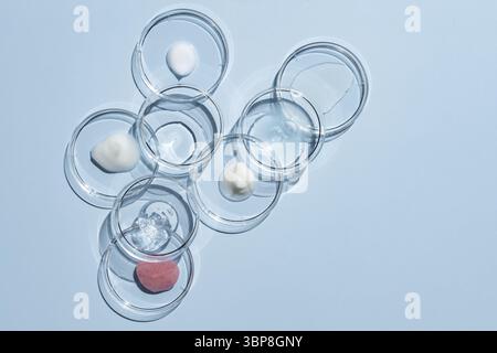 De nombreuses boîtes de Petri et différents échantillons de produits cosmétiques sur fond bleu, à plat. Espace pour le texte Banque D'Images