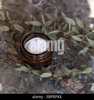 Crème pour le visage ou le corps dans un pot en verre foncé avec des extraits naturels et des huiles. Cosmétiques pour le soin de la peau. Traitement à base de plantes Banque D'Images
