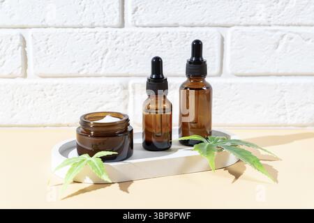 Sérum d'huile de chanvre cbd en flacon compte-gouttes en verre avec feuilles de cannabis, crème hydratante, sérum, lotion, huile essentielle. Feuilles de cannabis avec cosme de soin de la peau Banque D'Images