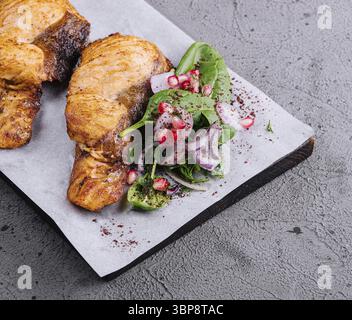 Nourriture, steak de saumon grillé servi sur une planche à découper en bois avec sauce blanche et salade de légumes frais sur fond gris texturé Banque D'Images