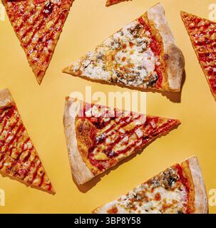Nourriture, tranches de pizza colorées sont dispersées sur une surface jaune vif. Chaque tranche présente différentes garnitures, mettant en valeur une variété de saveurs Banque D'Images