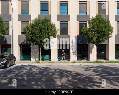Bologne, Italie 3 juillet 2025 piéton urbain se promenant devant une architecture élégante le long d'un paysage de rue verdoyant dans la ville historique de Bologne, capturant le contemporain Banque D'Images