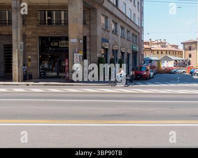 Bologne, Italie 3 juillet 2025 femme cycliste à travers la ville historique de Bologne, passant devant des bâtiments et des vitrines sous la lumière chaude du soleil pendant l'été Banque D'Images