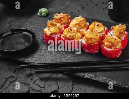 Nourriture, ce délice culinaire propose des rouleaux de sushi aux crevettes vibrants disposés soigneusement sur un plateau en pierre noire. Accompagné de sauce soja et wasabi, il regarde Banque D'Images
