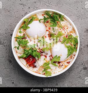 Nourriture, vue de dessus d'un bol avec des œufs pochés sur du yaourt, garni d'herbes Banque D'Images