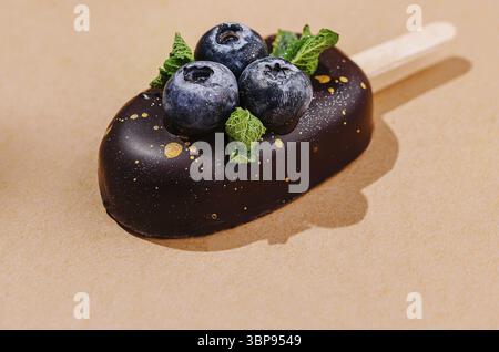 Nourriture, barres de crème glacée artisanales avec des myrtilles fraîches et du chocolat sur un fond neutre chaud Banque D'Images