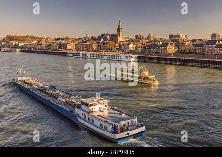 Vue panoramique de la ville néerlandaise de Nimègue pendant le coucher du soleil avec la rivière Waal et les bateaux en face Banque D'Images