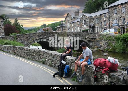 Promeneurs se reposant sur Afon Colwyn dans le village gallois de Beddgelert dans la région de Snowdonia à Gwynedd, pays de Galles Banque D'Images
