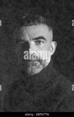 Portrait noir et blanc Moody d'un homme barbu mature aux cheveux courts, portant un col roulé foncé, partiellement éclairé avec une ombre dramatique. Banque D'Images