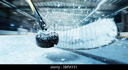 Gros plan d'une crosse de hockey frappant le palet sur la glace lors d'une action rapide sur une patinoire intérieure en 3D. Banque D'Images