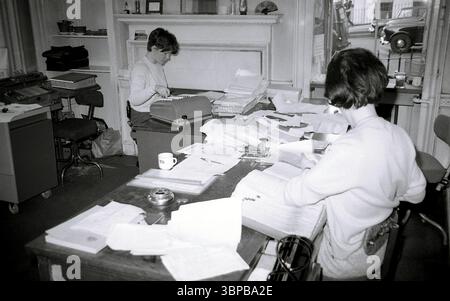 1966, historique, deux jeunes femmes travaillant dans le bureau municipal d'une compagnie maritime, Édimbourg, Écosse, Royaume-Uni, l'une utilisant une machine à ajouter de l'époque. Documents et dossiers couvrant les bureaux. Banque D'Images