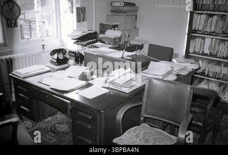 1966, historique, deux bureaux en bois recouverts de paperasse dans un coin d'un bureau de ville encombré d'une compagnie maritime, Édimbourg, Écosse, Royaume-Uni. Banque D'Images
