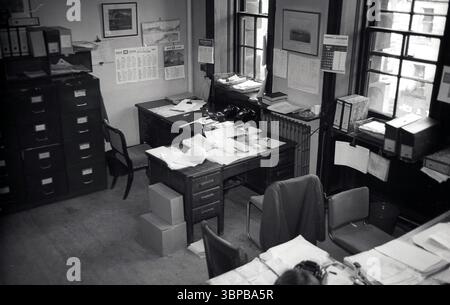 1967, historique, à l'intérieur d'un bureau municipal d'une compagnie maritime, Édimbourg, Écosse, Royaume-Uni. Des bureaux en bois avec de la paperasse, des classeurs sur les rebords de la fenêtre et des classeurs en métal, avec plus de classeurs empilés sur le dessus. Banque D'Images