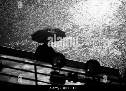 Années soixante, sport, football, Bundesliga, 1967/1968, MSV Duisburg v. SV Werder Brême 1-1, Wedau Stadium à Duisburg, match par temps pluvieux sous la lumière des inondations, l'homme avec parapluie est assis seul sur un banc comme une silhouette Banque D'Images