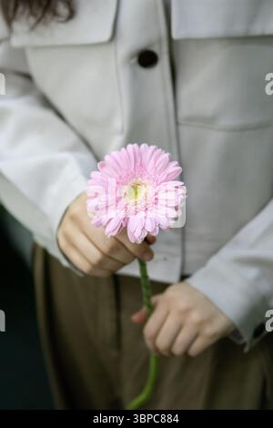 Femme tenant une fleur dans sa main. Composition de style de vie minimale et douce avec une beauté naturelle et une émotion féminine. Idéal pour le bien-être, la floraison, SK Banque D'Images