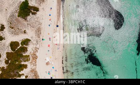 Plage de sable avec parasols vibrants et eau turquoise d'en haut Banque D'Images