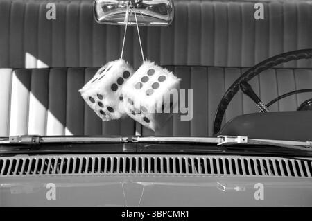Dés flous suspendus au rétroviseur d'une voiture classique en noir et blanc Banque D'Images