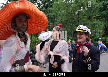 Trois individus en tenue vibrante sont capturés à l'extérieur. L'un porte un grand chapeau orange et des vêtements à motifs ; l'autre, un châle rose et un vêtement foncé Banque D'Images