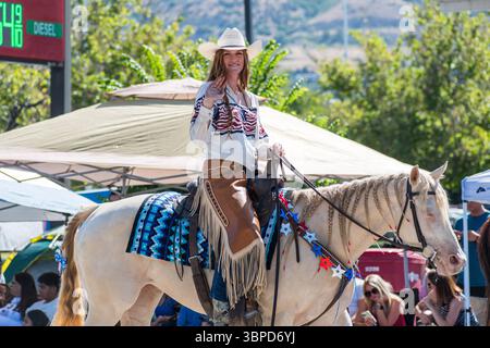 Provo, Utah – 4 juillet 2025 : une femme fait signe en montant à cheval pendant la grande parade du Freedom Festival dans le centre-ville de Provo. Banque D'Images