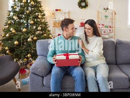 Homme ouvrant Un cadeau de Noël ou de nouvel an de Woman at Home Banque D'Images