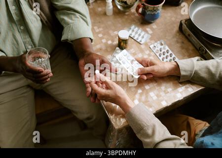 Couple multiethnique senior prenant des médicaments ensemble à Home table Banque D'Images